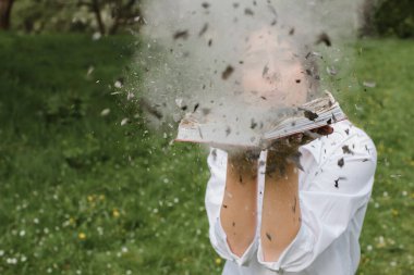 Yakıcı kitap ellerinde. Kitaplar ormanda yanıyordu. Yanan bir kitap tutan genç bir kız. Ormanda genç bir kadın bir kitap yakıyor. Seçici odak  