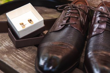 Erkekler için kahverengi çantalar ve altın alyanslar, ahşap bir yüzeyde, düğün için hazırlanıyorlar.