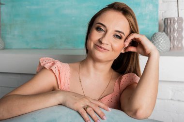 Genç duygusal bir kızın portresi. Bir ışık odasında bir sandalyede oturuyor. Gülümsüyor, şaşırıyor, zevk alıyor.