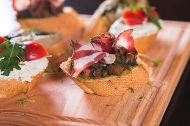 Sebzeli lezzetli ve çeşitli sandviçler ve ahşap tepside kurutulmuş et.