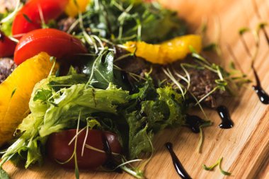 Taze sebze salatası. Koyu bir arka planda, ahşap tepside et parçaları.