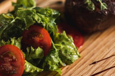 Sağlıklı yağsız biftek, orta pişmiş biftek, kızarmış patates ve meyhanede yeşil salata, ahşap tepsi. Manzarayı kapat. Menü için 