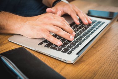 Dizüstü bilgisayarla çalışan genç bir adam, dizüstü bilgisayarda çalışan bir adam, iş yerinde çalışan bir adam.