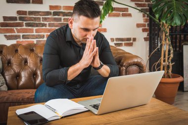 Evde dizüstü bilgisayar ve kağıtlarla çalışan genç bir iş adamı.