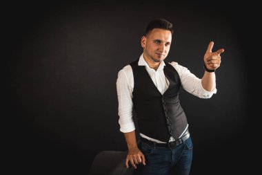 Genç ve çekici iş adamı, müşteri için metin ya da öğe eklemek için avuç üzerinde boş fotokopi alanı gösteriyor, mutlu ve heyecanlı görünüyor, beyaz gömlekle koyu arka planda izole edilmiş. 