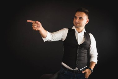 Genç ve çekici iş adamı, müşteri için metin ya da öğe eklemek için avuç üzerinde boş fotokopi alanı gösteriyor, mutlu ve heyecanlı görünüyor, beyaz gömlekle koyu arka planda izole edilmiş. 