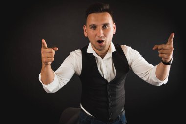 Genç ve çekici iş adamı, müşteri için metin ya da öğe eklemek için avuç üzerinde boş fotokopi alanı gösteriyor, mutlu ve heyecanlı görünüyor, beyaz gömlekle koyu arka planda izole edilmiş. 