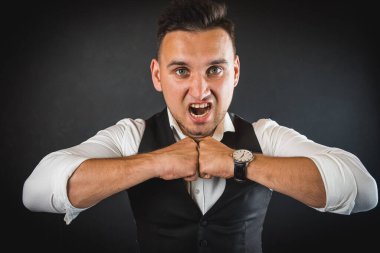 Beyaz gömlekli ve yelekli bir adam dikilip kameraya bakıyor. Adam yumruklarıyla ellerini onun önünde tutuyordu. Zalim bir adam, karanlık bir geçmişi olan duygusal bir adam..