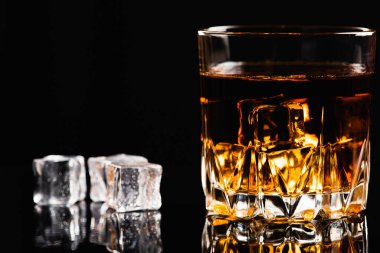 Düşük anahtar, bir bardak viski, konyak ya da yakınlarda dağılmış burbon buzu, eski moda, fotokopi alanı, seçici odak, metin yazılacağı yer.