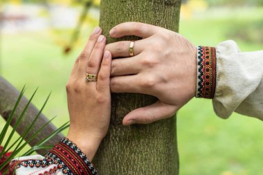 Yeni evlilerin ellerinin üst görüntüsü. Gelin ve damat parkta el ele tutuşuyorlar.