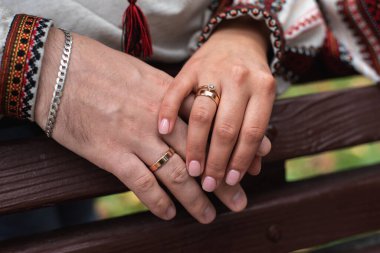Yeni evlilerin ellerinin üst görüntüsü. Gelin ve damat parkta el ele tutuşuyorlar.