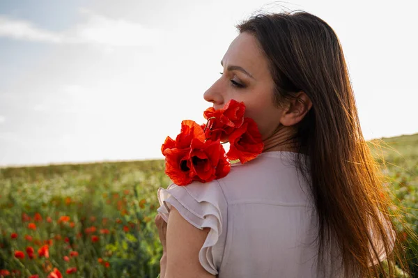 Açık renk elbiseli, elinde kırmızı gelinciklerle altın saat çiçekli çayırlarda gezen sakin yaz manzarası, romantik ruh hali, farkındalık, doğa, özgürlük, yaşam tarzı