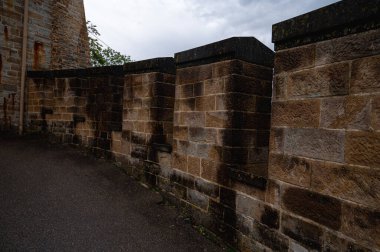 Kırsal taştan bir duvar, dar pencereler ve klasik bir fenerin yer aldığı bir ortaçağ Avrupa kale avlusunun mimari ayrıntıları. Tarihin, gücün ve fantezinin sembolü.