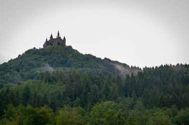 Muhteşem Hohenzollern Şatosu Almanya 'da bir orman tepesinde dramatik bulutlu bir gökyüzünün altında. Swabian Alpleri 'nde tarihi ve peri masalı gibi ünlü bir kale.