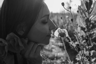 Uçsuz bucaksız gökyüzünün altındaki haşhaş tarlasında bir kadının doğayla olan özgürlük ve bağını yakaladığı düşük açılı, siyah beyaz bir görüntü.