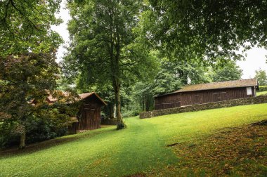Ağaçların arasına yerleşmiş ahşap ahırlar olan yemyeşil yamaçlar. Huzurlu kırsal yaşam, doğal güzellik ve Avrupa 'nın huzurlu kırsal manzarasını anımsatıyor. Seyahat ve doğa temaları için mükemmel.