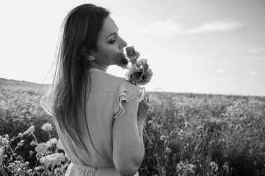 Çiçekler arasında mutlu bir kadının güzel siyah beyaz portresi. Monokrom tonu doğadaki bu dingin ve neşeli ana sonsuz, klasik bir his katar.