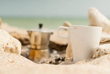 Kamp ateşinin yanında deniz kenarında kahve.