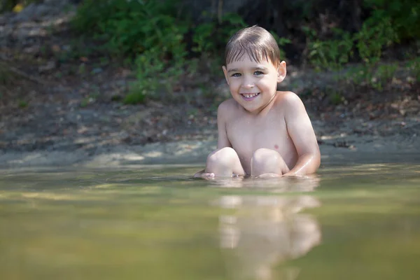 Happy little boy swimming in the lake
