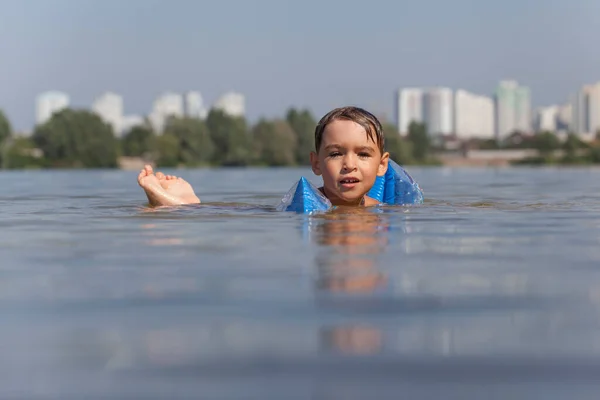 Happy little boy swimming in the lake