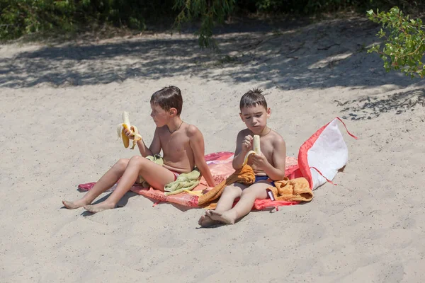 Dos Chicos Sentados Una Playa Arena Comiendo Plátanos — Foto de Stock