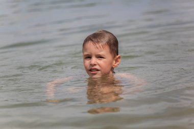 Mutlu küçük çocuk gölde yüzüyor.
