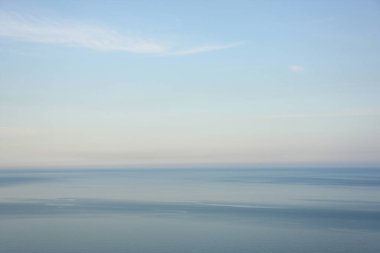 Mavi suları, gökyüzü ve bulutları olan deniz. Deniz manzarasının üzerinde gün batımı