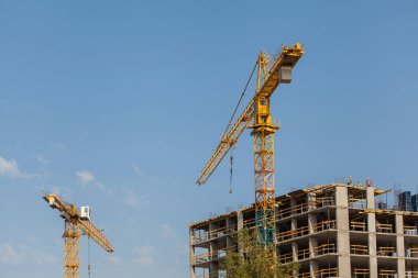 Mavi gökyüzüne karşı vinçleri olan inşaat alanı
