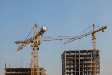 Mavi gökyüzüne karşı vinçleri olan inşaat alanı