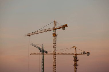 Gökyüzü arka planında vinçleri olan bir inşaat alanı. Gökyüzüne karşı kule inşaatı vinçleri