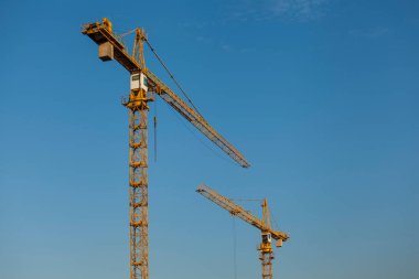 Mavi gökyüzünün arka planında kule inşaat vinçleri
