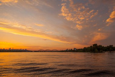 Gün batımında nehir manzarası. Parlak akşam bulutları