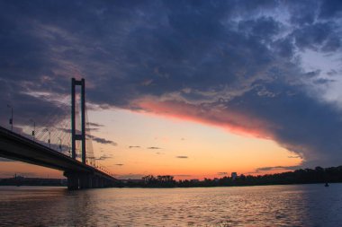 Akşam manzarası ve batan güneşin altında bir köprü. Kiev 'deki güney köprüsü