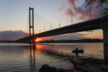 Akşam manzarası ve batan güneşin altında bir köprü. Kiev 'deki güney köprüsü