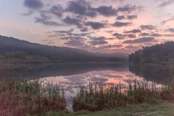Autumn landscape - lake at dawn against the backdrop of a beautiful cloudy sky