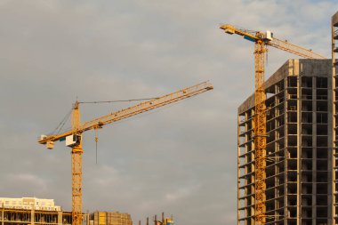 Bulutlu gökyüzüne karşı vinçleri olan inşaat alanı