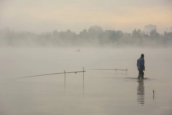 日出时在雾蒙蒙的湖上钓鱼的人 — 图库照片