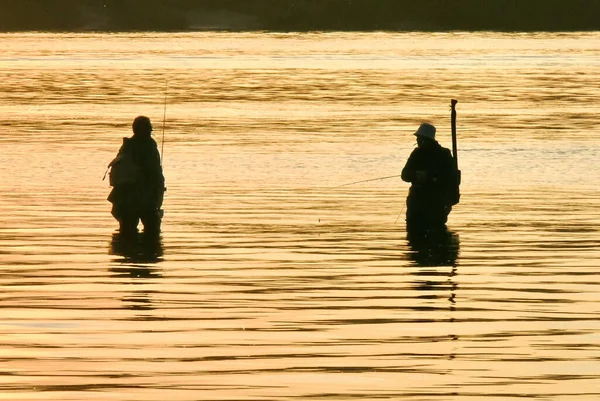 Silhuetas Dois Pescadores Água Com Varas Giratórias Pôr Sol — Fotografia de Stock