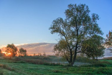 Güneşin doğuşunda gölün kıyısında