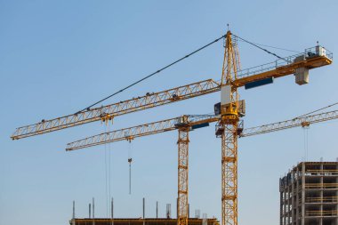 Mavi gökyüzüne karşı vinçleri olan inşaat alanı