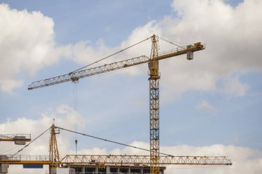 Bulutlu gökyüzüne karşı vinçleri olan inşaat alanı