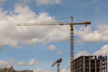 Bulutlu gökyüzüne karşı vinçleri olan inşaat alanı