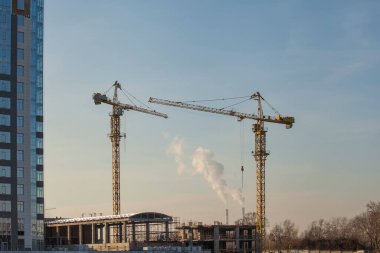 Mavi gökyüzüne karşı vinçleri olan inşaat alanı