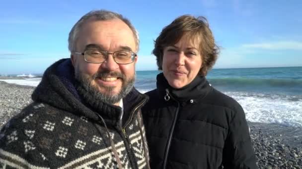 Ένα ώριμο ζευγάρι περπατά στην παραλία της Μεσογείου, σε μια ηλιόλουστη χειμωνιάτικη ημέρα. — Αρχείο Βίντεο