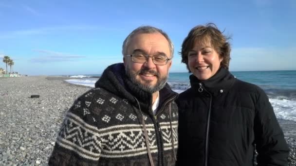 Una coppia matura cammina sulla spiaggia mediterranea in una giornata invernale soleggiata . — Video Stock