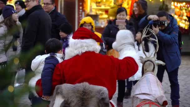 Santa geeft cadeaus aan kinderen op de kerstmarkt — Stockvideo