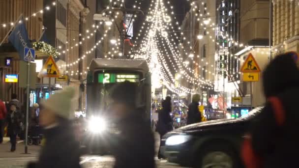 Tranvías brillantes en las calles céntricas de Helsinki durante la Navidad. Mucha gente, ventas navideñas y decoraciones brillantes . — Vídeo de stock