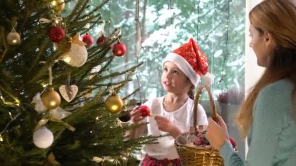 Pouco bonito menina com sua mãe decorar a árvore de Natal — Vídeo de Stock