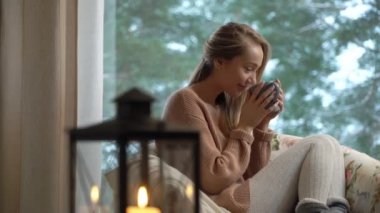 Mutlu kadın zevk büyük pencerenin kış kar ağaç arka plan ile sıcak kahve oturan ev Kupası