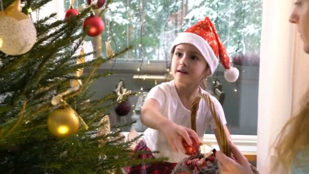 Aranyos kislány anyukája díszíteni a karácsonyfát — Stock videók